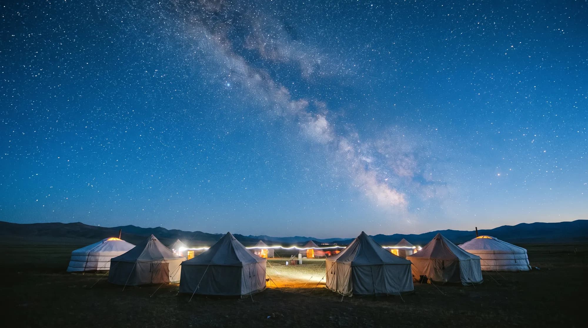 Camp de tentes et de yourtes éclairées sous la Voie lactée dans la steppe